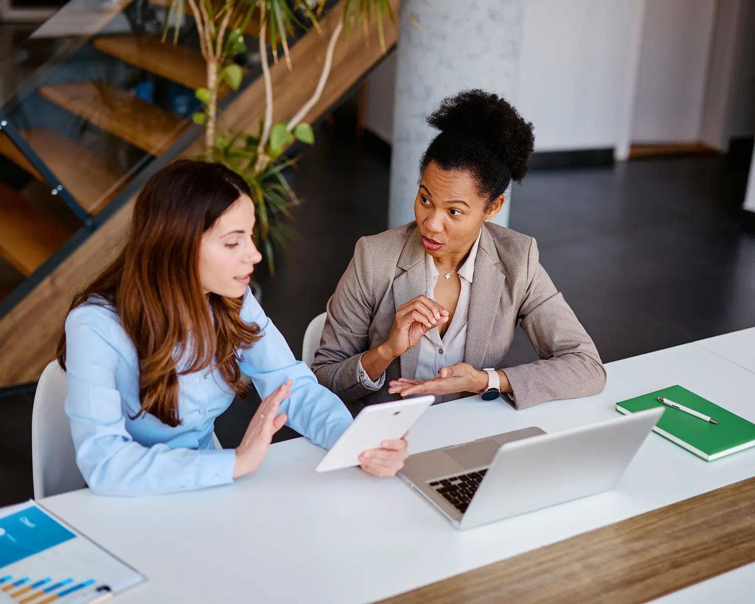 Women discussing work at office desk